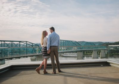 A couple poses together on the balcony of the Hunter Museum with the blue pedestrian bridge in the background.