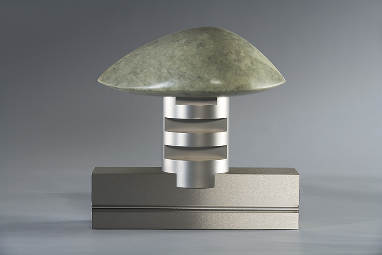 A metallic sculpture with a stone disk on top of a cylinder.