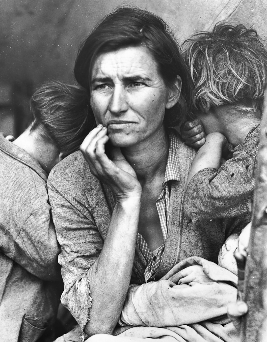 Black and white image of a woman looking into the distance with two children clung to her.