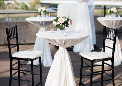 Small tables with white tablecloths and black chairs set up on the Hunter Museum balcony.