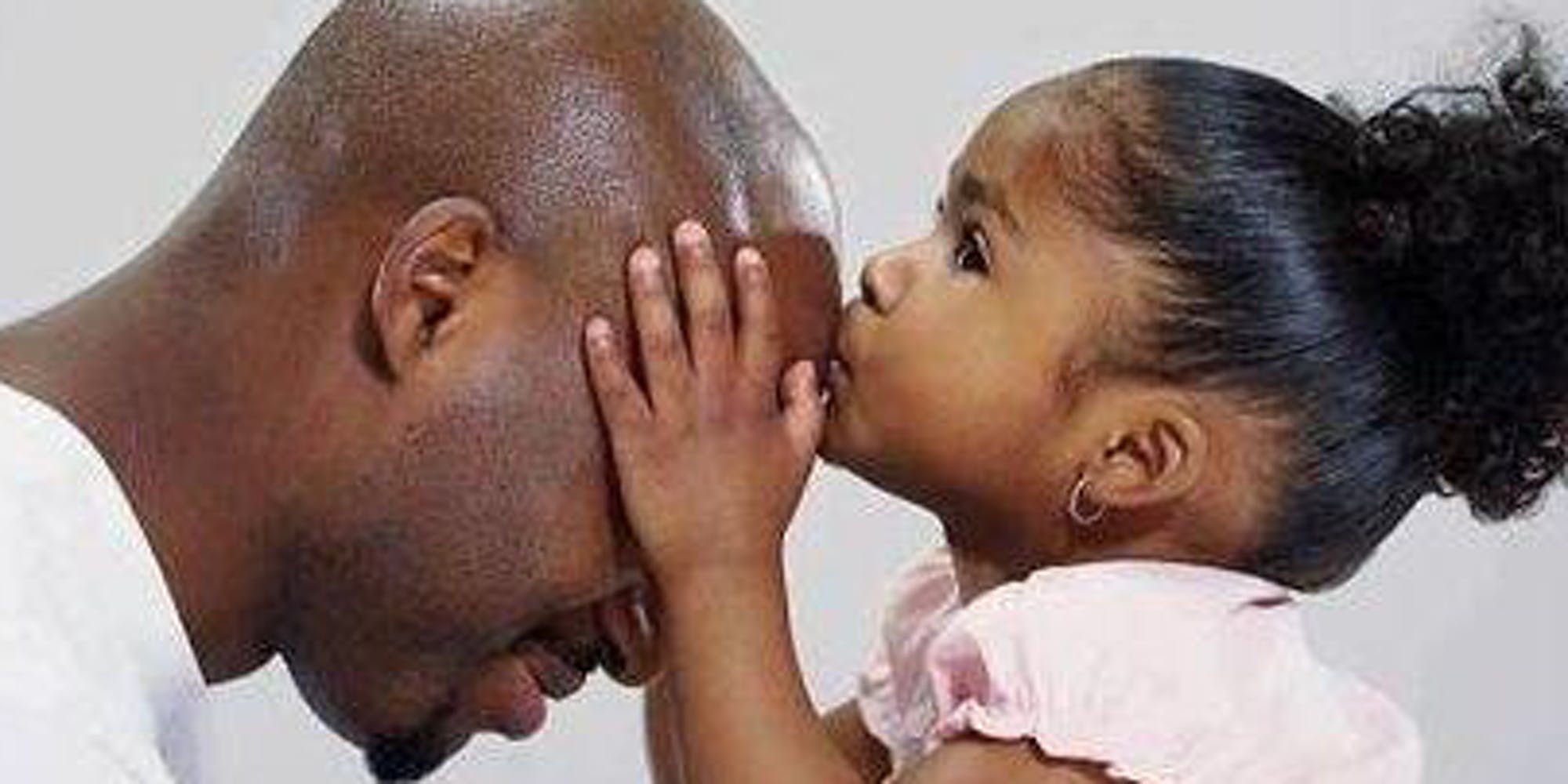 A young daughter kissing her father's head.
